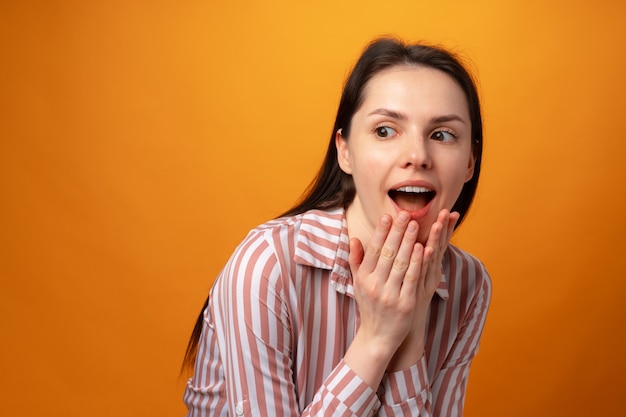 Garota chocada e surpresa gritando contra um fundo rosa