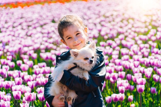 Garota com cabelo comprido cheirando a flor de tulipa em campos de tulipas