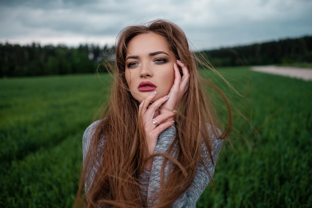 Garota com cabelo comprido em pé no campo ao vento