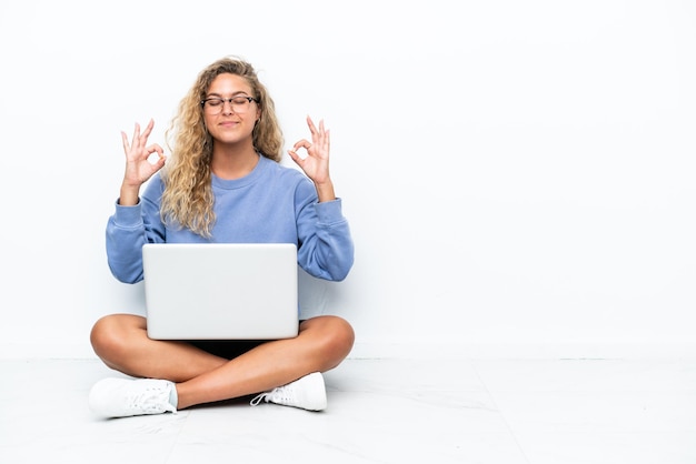 Garota com cabelo encaracolado com um laptop sentada no chão em pose zen