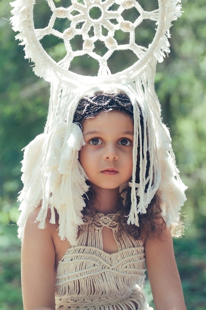 Garota com cabelo encaracolado escuro vestida como nativa da floresta com um apanhador de sonhos