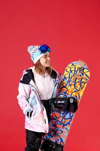 Garota com equipamento de neve segurando uma prancha de snowboard