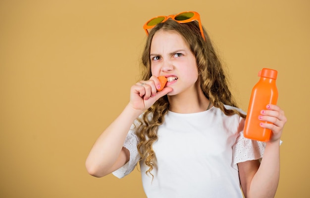 Garota com raiva bebe suco de cenoura fresco. férias de verão. menina de óculos da moda. Nutrição vitamínica. suco de vitamina refrescante. Saúde. Dieta vitamínica de verão. Fonte natural de vitaminas. comida saudável.