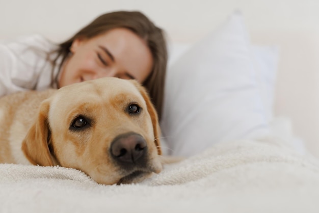 garota com roupas brancas com cachorro labrador brincando em casa