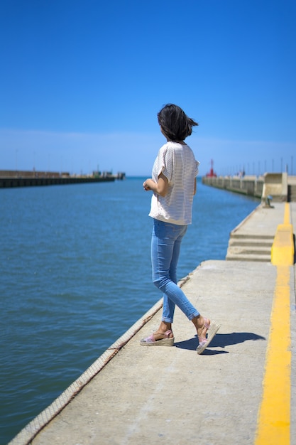 Garota com roupas casuais de férias, caminhando por um porto italiano no verão