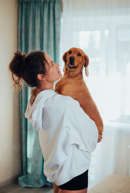 Garota com roupas de casa segurando um cachorro nos braços