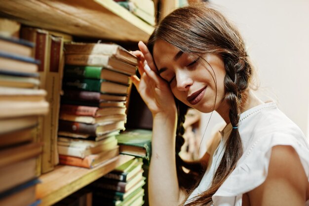 Garota com tranças na blusa branca na antiga biblioteca