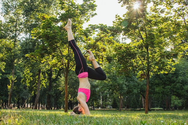 garota com um agasalho leve fazendo ioga no parque à tarde no verão