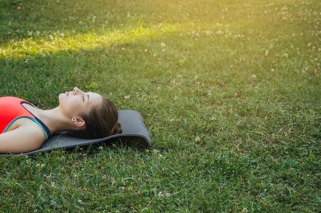 garota com um agasalho leve fazendo ioga no parque à tarde no verão