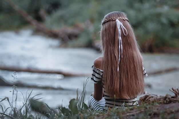 Garota com um longo cabelo, olhando a vista deslumbrante sobre o lago.