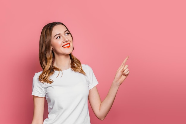 Garota com uma camiseta branca sorri e aponta o dedo para o espaço da cópia