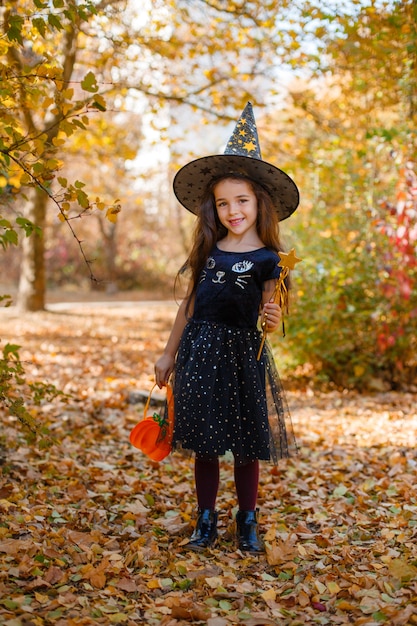 Garota com uma fantasia de bruxa para o halloween no outono park