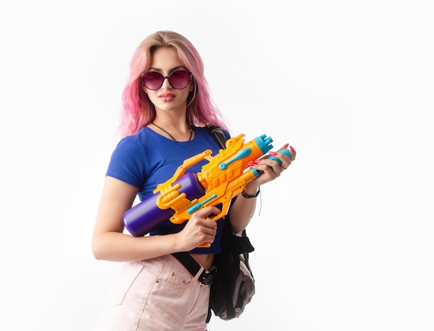 Garota com uma pistola de água em roupas de verão magras e sexy isoladas em um fundo branco