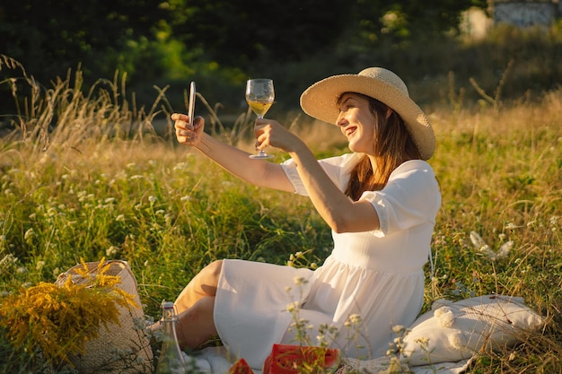 Garota com uma taça de champanhe ou vinho branco fazendo uma selfie no telefone pessoas usando tecnologia