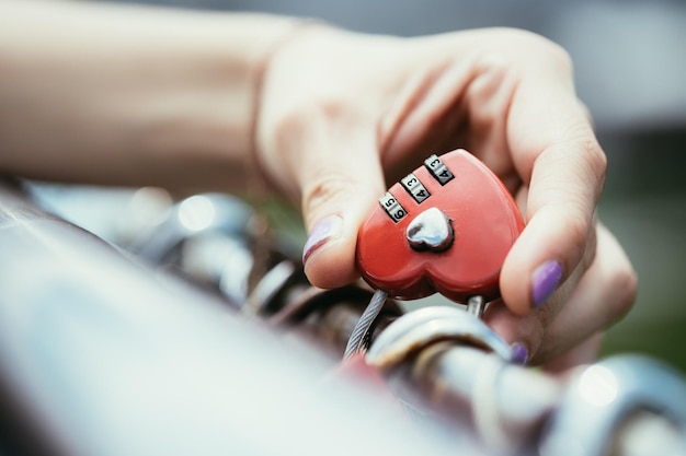 Garota com unhas coloridas está segurando um cadeado de amor em Markatsteg Salzburg