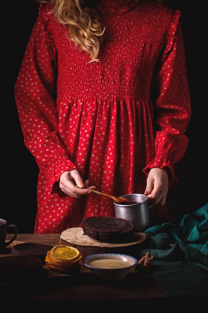 Garota com vestido vintage vermelho preparando um bolo de chocolate com cerejas