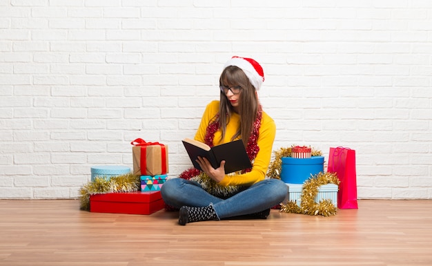 Garota comemorando as férias de natal segurando um livro e desfrutando de leitura