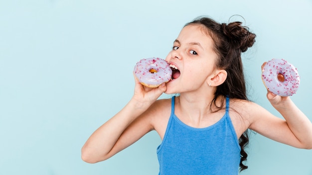 Garota comendo deliciosos donuts com cópia-espaço