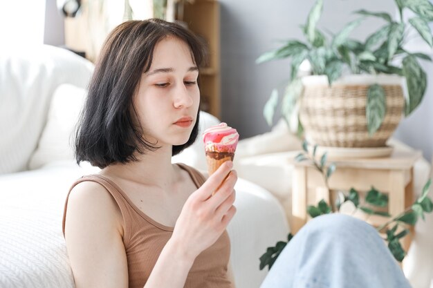 Garota comendo sorvete com fundo de sala em casa. Menina criança gosta de comer e conceito de fome.