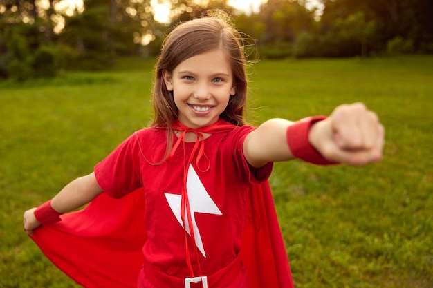 Garota corajosa em capa de super-herói no parque