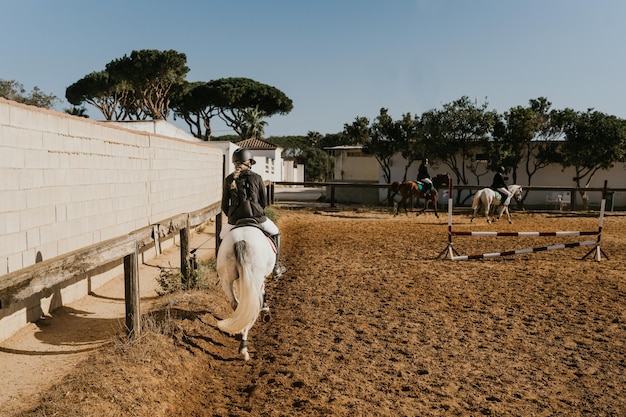 Garota correndo um cavalo branco em torno de uma arena equestre