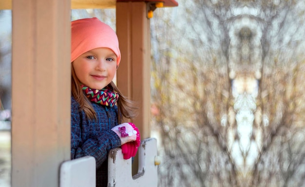 Garota de 5 anos para passear no parque em um dia de primavera Garota de chapéu e luvas primavera