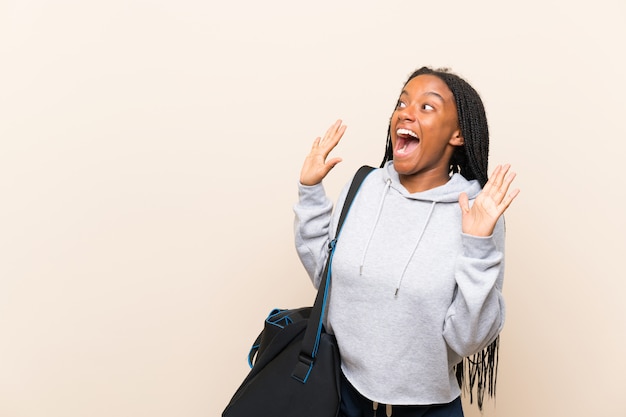 Garota de adolescente esporte americano africano com longos cabelos trançados com expressão facial de surpresa