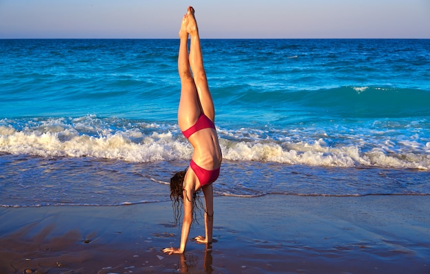 Garota de biquíni de ginástica acrobática em uma praia