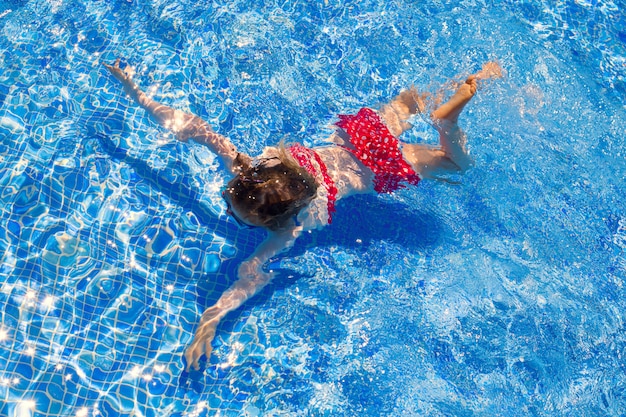 Garota de biquíni garota nadando na piscina de azulejos azuis