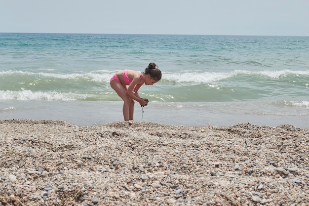 Garota de biquíni rosa brincando alegremente na praia em um dia ensolarado de verão Vera Espanha