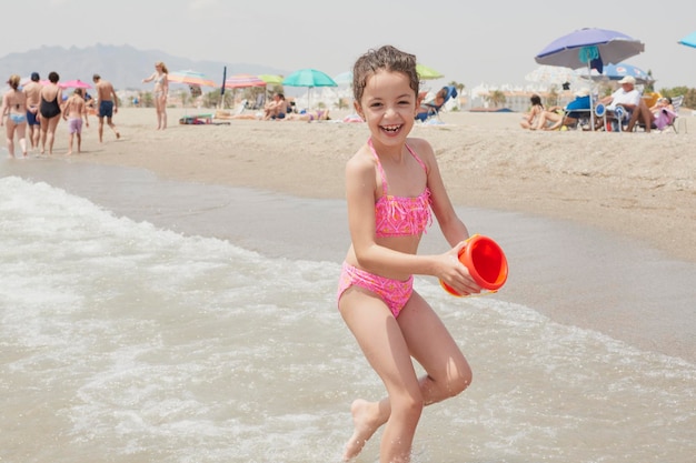 Garota de biquíni rosa brincando alegremente na praia em um dia ensolarado de verão Vera Espanha