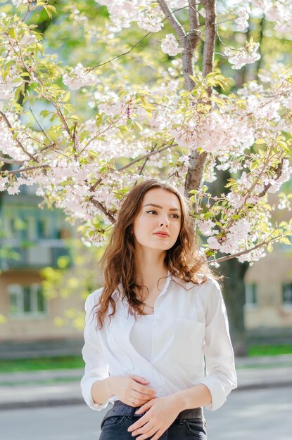 garota de camisa branca fica perto do sol de primavera de sakura