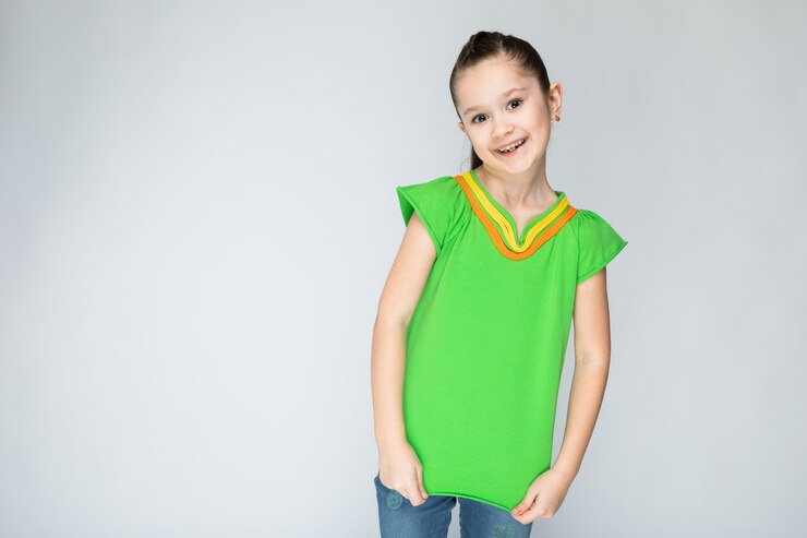 Foto garota de camiseta verde e calça jeans azul sobre fundo cinza.