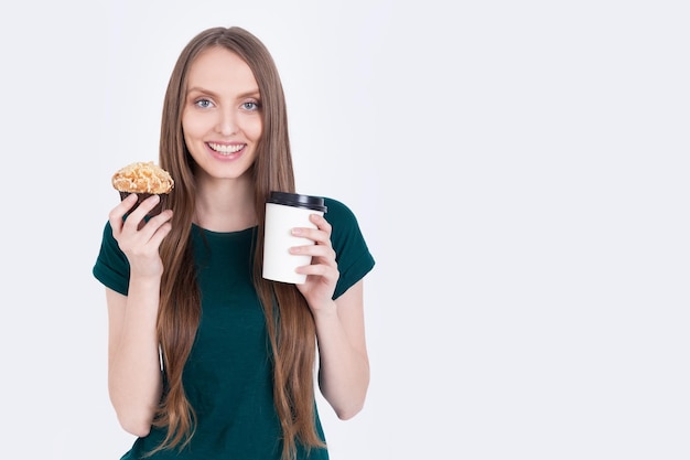 Garota de camiseta verde segurando cupcake e café