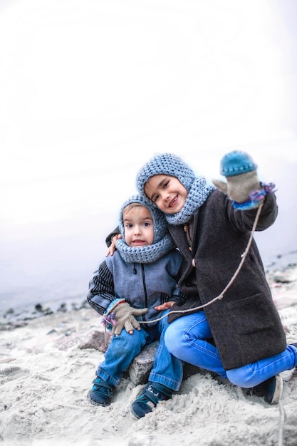 Garota de chapéu cinza tricotado compartilhando luvas com seu irmão congelado