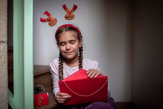 Garota de chapéu divertido escreve carta para o Papai Noel e espera ansiosamente por presentes nas férias de inverno do Natal