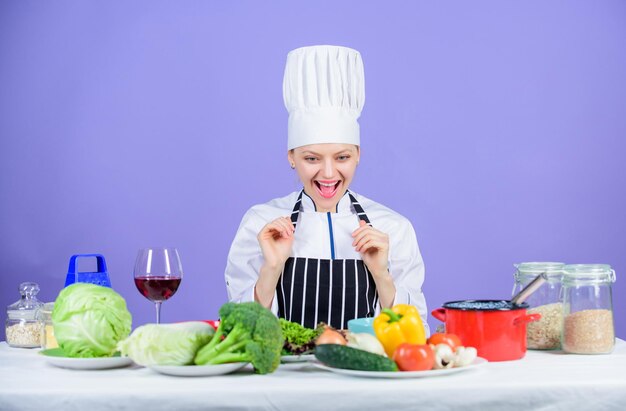 Garota de chapéu e avental Cozinhando comida saudável Ingredientes de legumes frescos para cozinhar refeição Vamos começar a cozinhar Chef de mulher cozinhando comida saudável Receitas gourmet do prato principal Conceito de receita deliciosa