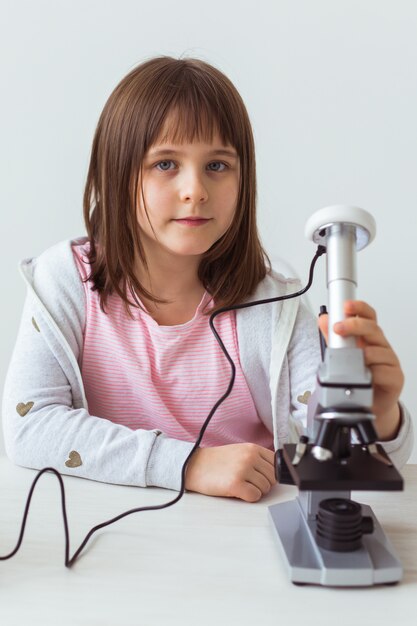 Garota de criança na aula de Ciências, usando microscópio digital. Tecnologias, crianças e conceito de aprendizagem.