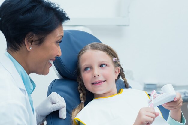 Garota de ensino dentista feminina como escovar os dentes na cadeira de dentista