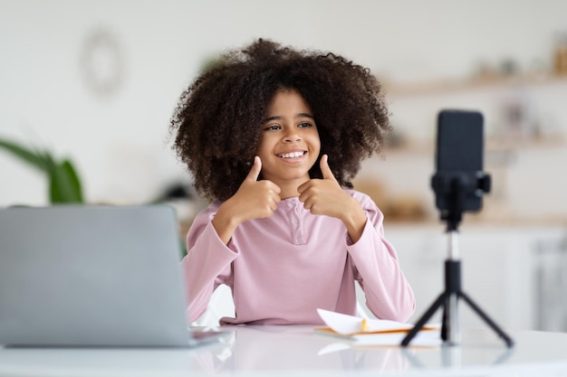 Garota de escola afro-americana inteligente gravando vídeo enquanto estudava