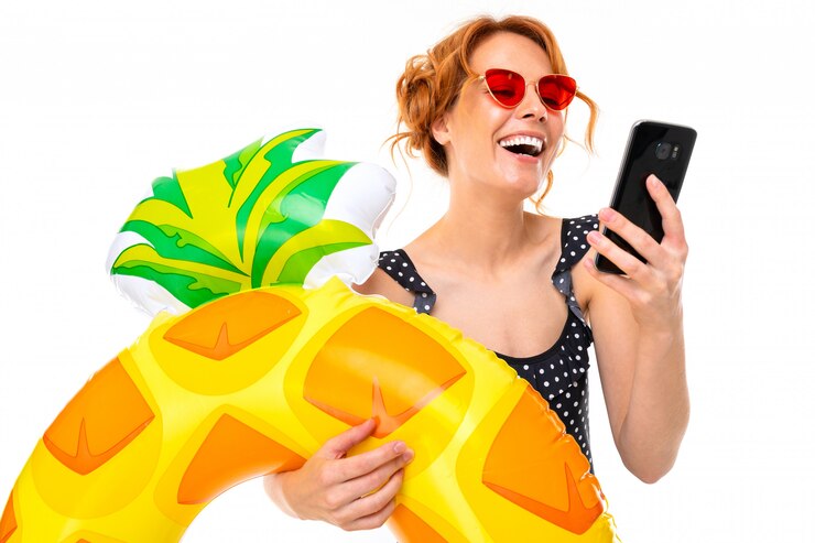 Foto garota de férias à beira-mar com um círculo de natação senta-se na internet com um smartphone