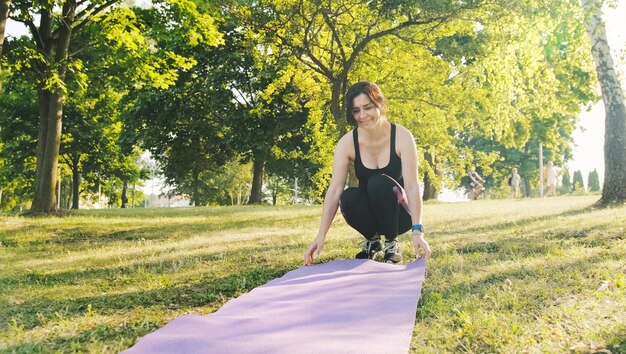 garota de fitness com um mapa para ioga preparando-se para praticar ioga recreação ao ar livre e exercícios de treino