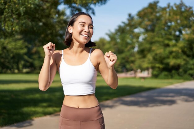 Garota de fitness feliz alcança a maratona de meta correndo com as mãos para cima comemorando a vitória enquanto corre