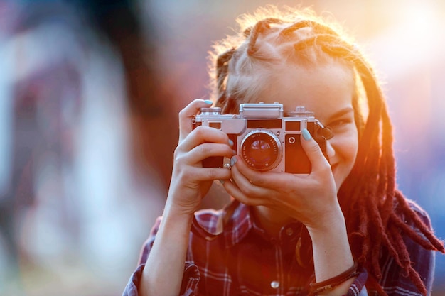 Garota de fotografia atraente hipster com dreads atirando no local da natureza no pôr do sol na vista ao ar livre da floresta