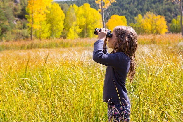 Garota de garoto binocuar explorer na natureza outono amarelo