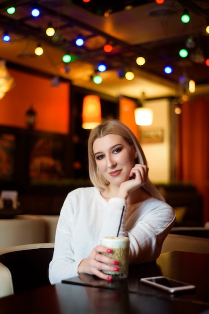 Garota de inverno está bebendo café. Ela gosta de seu cappuccino ou branco puro.