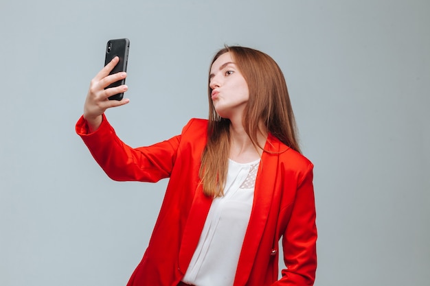 Garota de jaqueta vermelha tirando uma selfie ao telefone