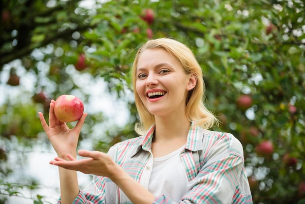 Garota de jardineiro de pomar de frutas de verão colheita de primavera no jardim de maçãs vitamina e dieta alimentos saudáveis dentes fome Mulher feliz comendo natureza maçã verde Almoço no parque colheita de outono