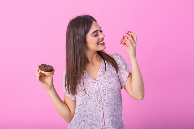 Garota de modelo de beleza comendo rosquinhas coloridas.