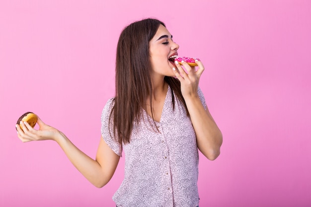 Garota de modelo de beleza comendo rosquinhas coloridas.